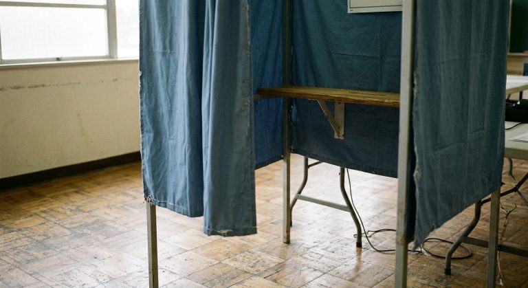 An empty voting booth with blue curtains at a polling place